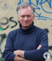 Christian Springer mit verschränkten Armen vor Wand mit Graffiti